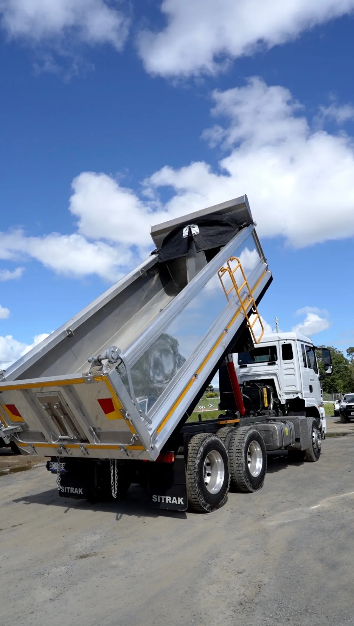 SITRAK G5S 6x4 tipper tray fully raised, mid-tip on a Gold Coast site